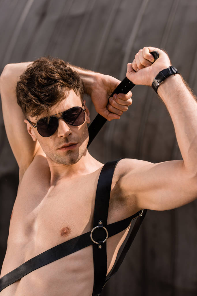 стильний сексуальний чоловік в чорних сонцезахисних окулярах і мечовому поясі
 - Фото, зображення