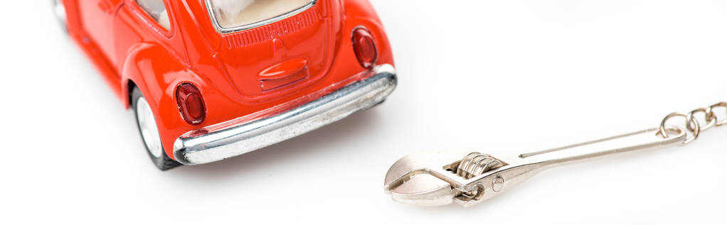 colpo panoramico di auto giocattolo rosso e chiave su superficie bianca
 - Foto, immagini