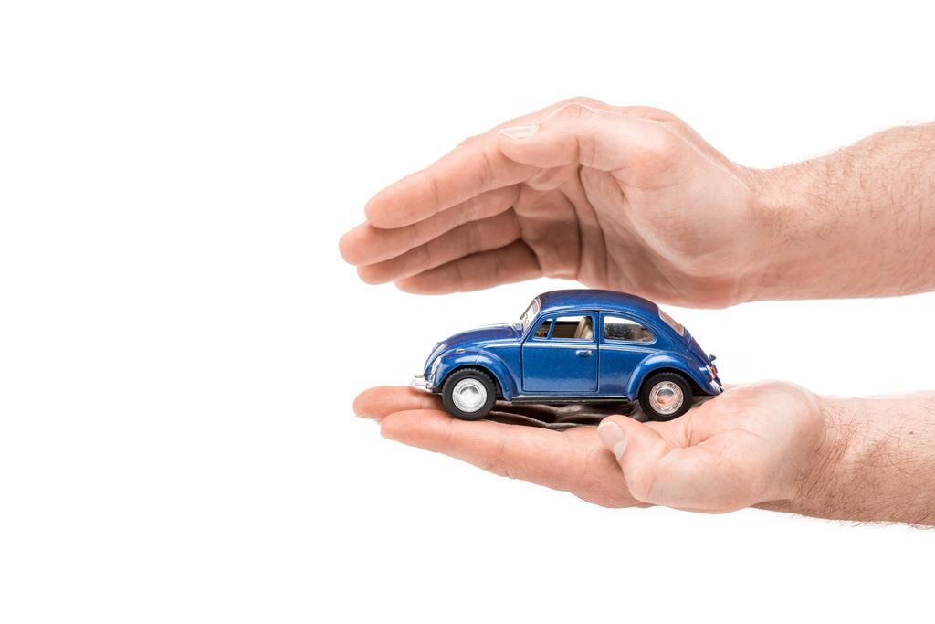обрізаний вид людини, що тримає синій іграшковий автомобіль ізольований на білому
 - Фото, зображення