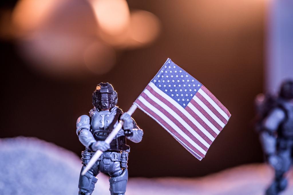 επιλεκτική εστίαση του αστροναύτη παιχνιδιών που κατέχει εθνική αμερικάνικη σημαία στο διάστημα  - Φωτογραφία, εικόνα