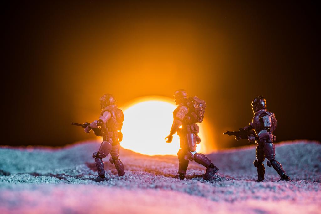 Spielzeugsoldaten-Silhouetten mit Gewehren, die auf einem Planeten mit Sonne im Hintergrund laufen - Foto, Bild