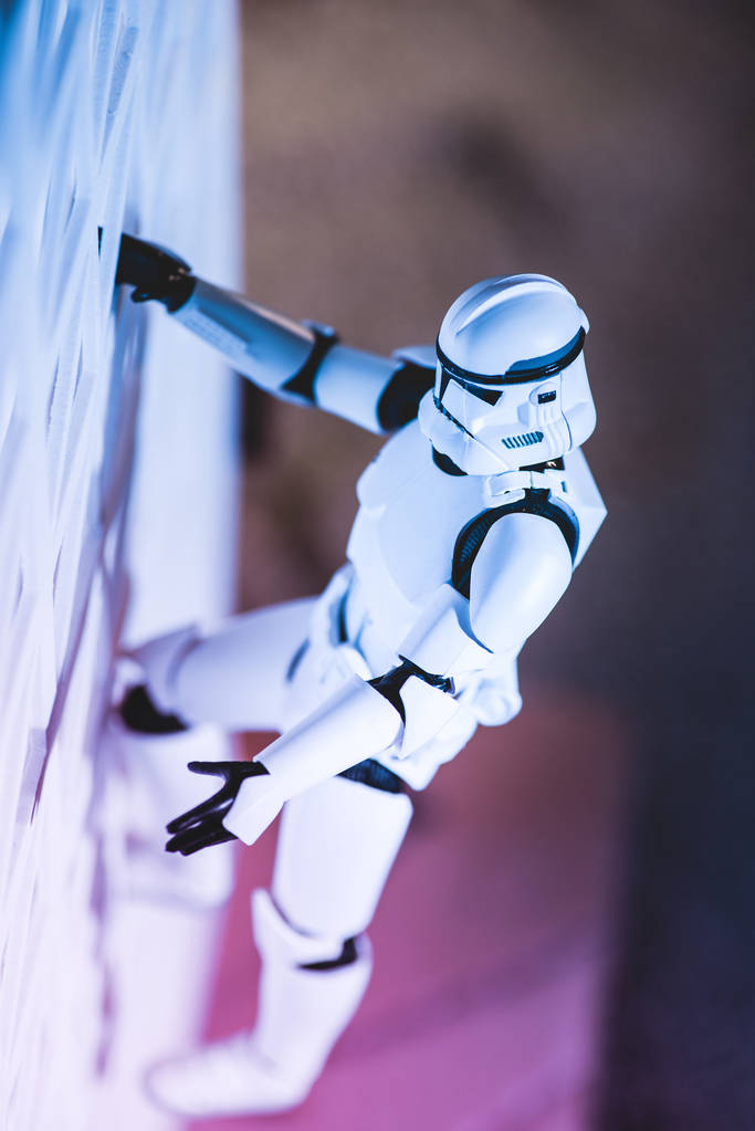 plastic Imperial Stormtrooper figurine climbing white textured wall - Φωτογραφία, εικόνα