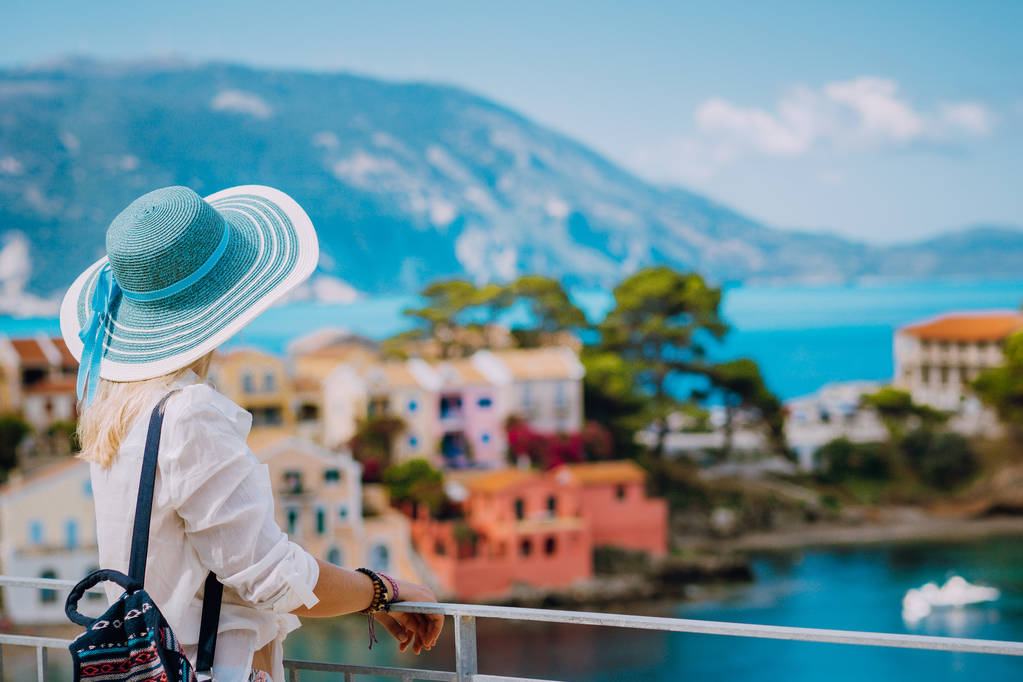 かわいいカラフルな小さなアッソス村で太陽の帽子を持つ観光ブロンドの女性。ケファロンニア(ギリシャ) - 写真・画像