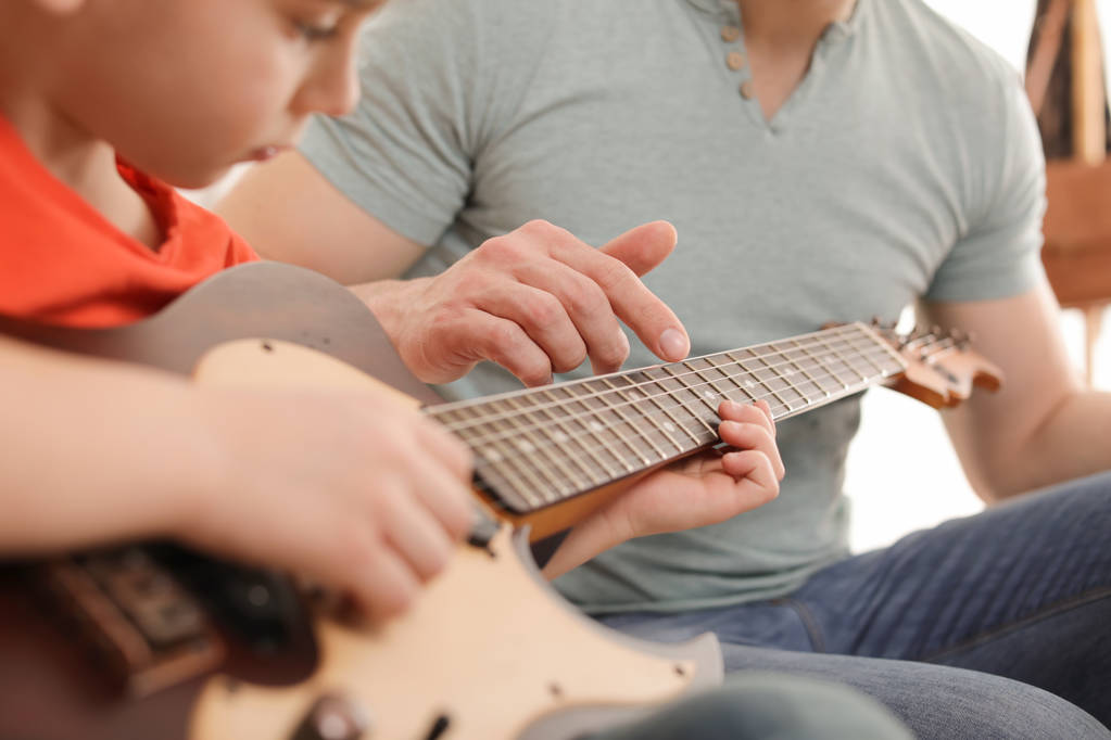 Ragazzino che suona la chitarra con il suo insegnante a lezione di musica, primo piano. Note di apprendimento
 - Foto, immagini