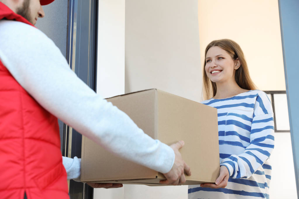 Woman receiving parcel from delivery service courier indoors - Photo, Image