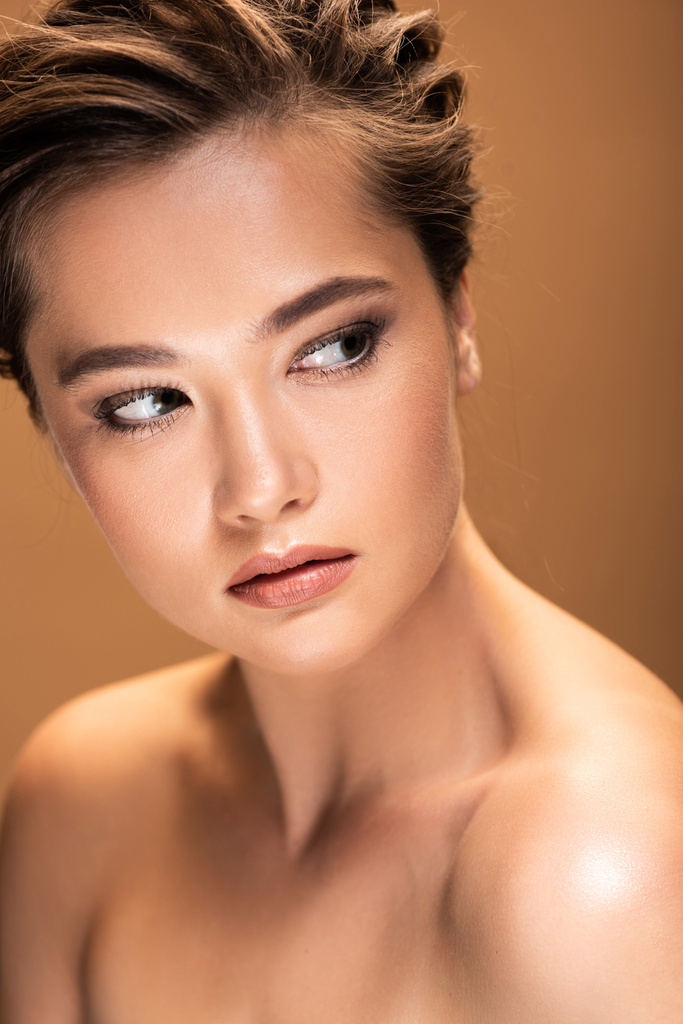 beautiful naked woman with shiny makeup looking away isolated on beige - Photo, Image