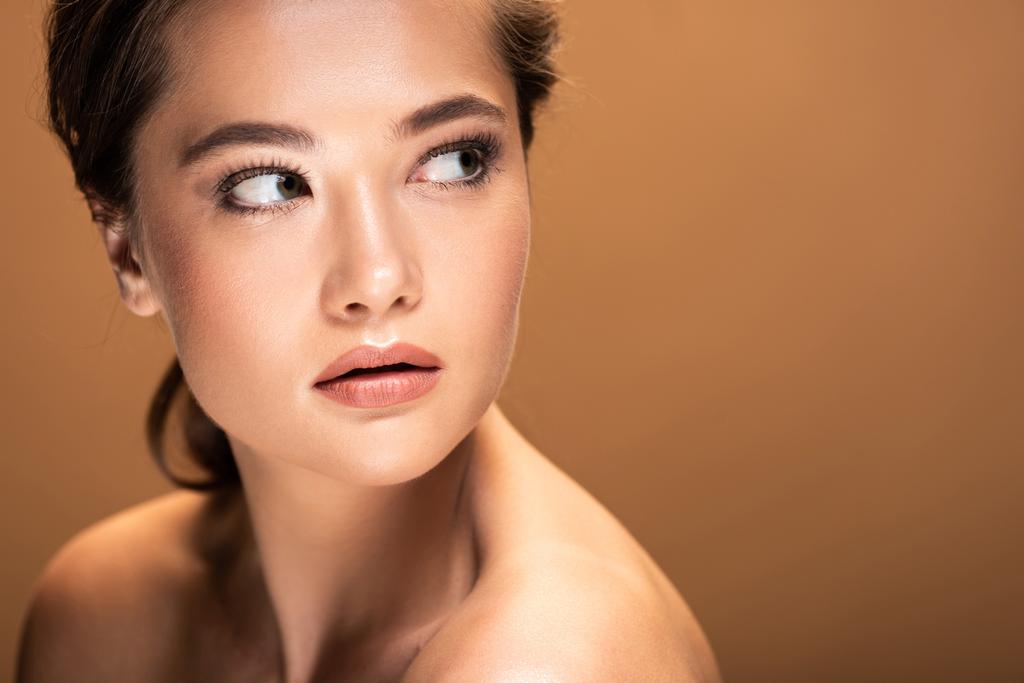 jeune belle femme nue avec maquillage brillant regardant loin isolé sur beige avec espace de copie
 - Photo, image