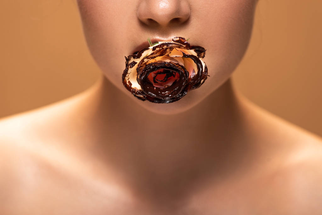 vue recadrée de femme nue tenant rose dans la bouche recouverte de chocolat fondu isolé sur beige
 - Photo, image