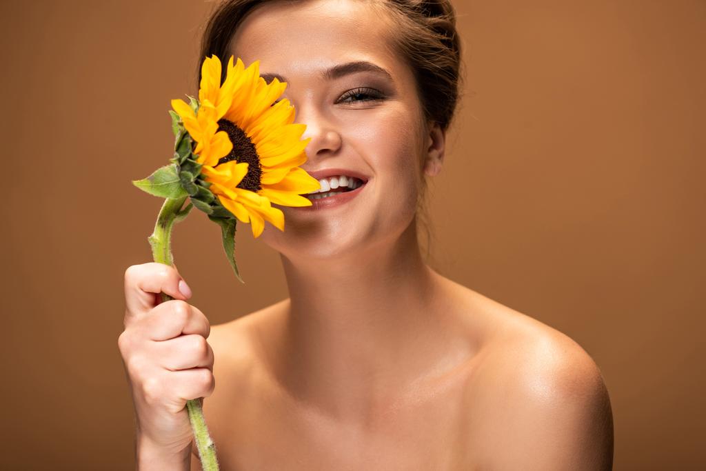 glücklich lachend schöne nackte Frau mit gelben Sonnenblumen isoliert auf braun - Foto, Bild