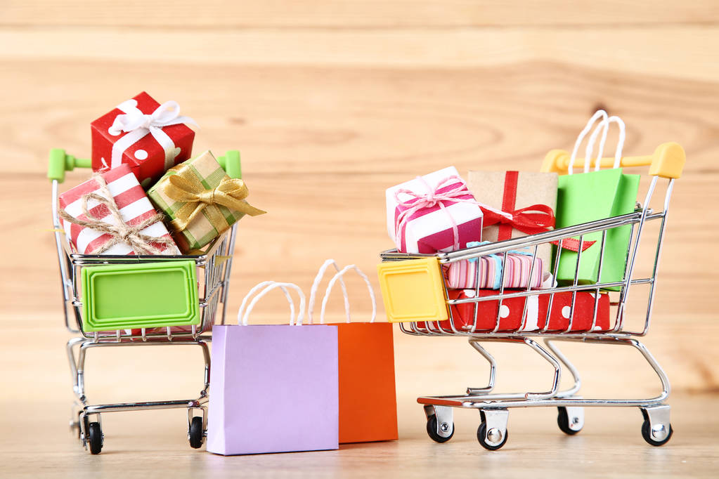 Carrelli con confezioni regalo e shopping bag su legno marrone ta
 - Foto, immagini