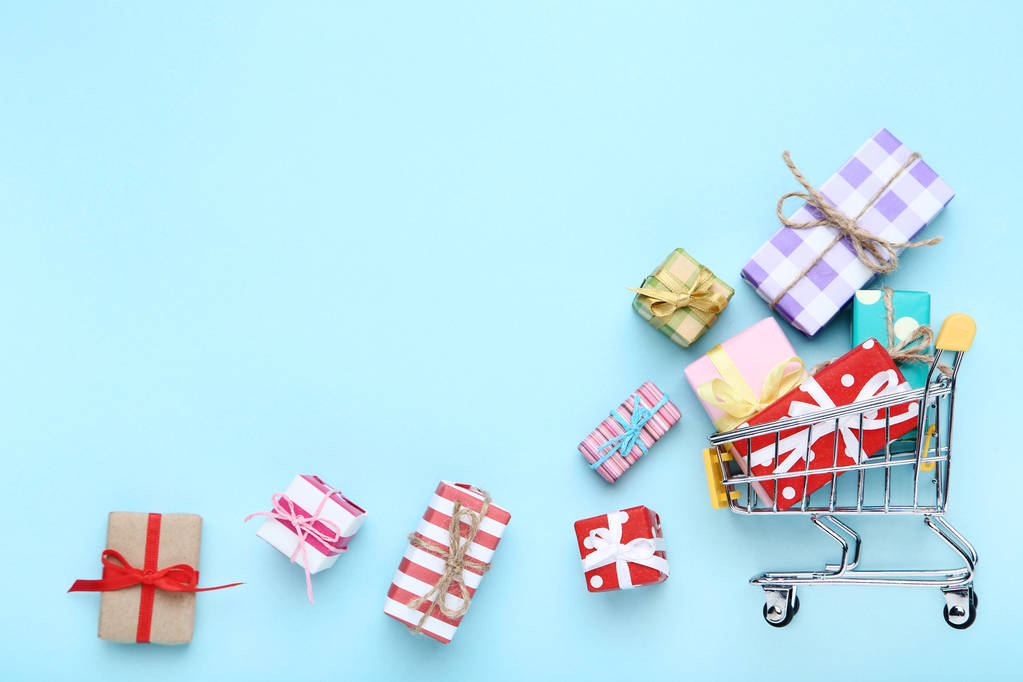 kleiner Warenkorb mit Geschenkboxen auf blauem Hintergrund - Foto, Bild