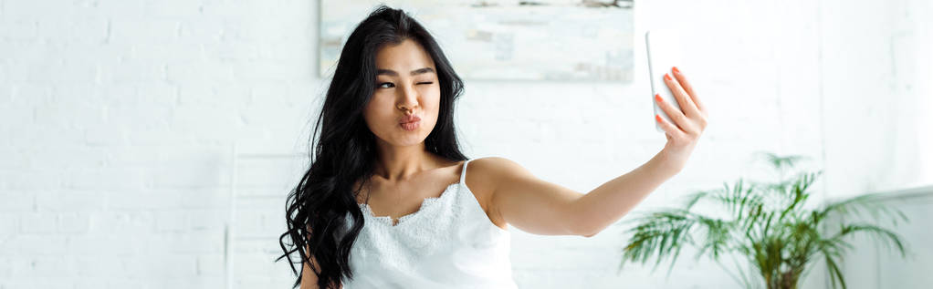 plano panorámico de chica asiática con cara de pato tomando selfie en teléfono inteligente
  - Foto, imagen