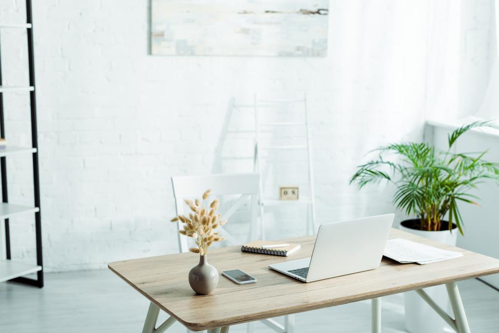 Laptop und Smartphone mit leerem Bildschirm auf Holztisch im modernen Büro  - Foto, Bild