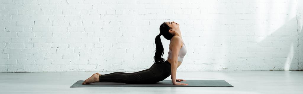 plan panoramique de belle femme thai brune faisant de l'exercice sur tapis de yoga
  - Photo, image