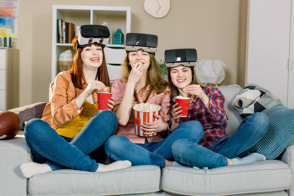technology, virtual reality, cyberspace, entertainment and people concept - happy young women with virtual reality headset or 3d glasses sitting on sofa at home - Photo, Image