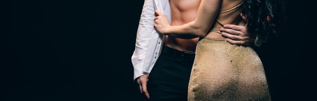 vue recadrée de l'homme avec torse musculaire étreignant petite amie avec des fesses sexy isolé sur noir, panoramique shot
 - Photo, image