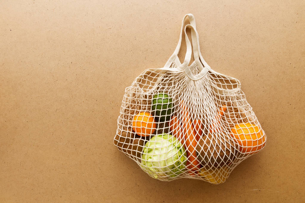 Çevre dostu yeniden kullanılabilir ağ örgüsü, meyve ve sebzelerle örülmüş alışveriş torbası, sıfır atık. - Fotoğraf, Görsel