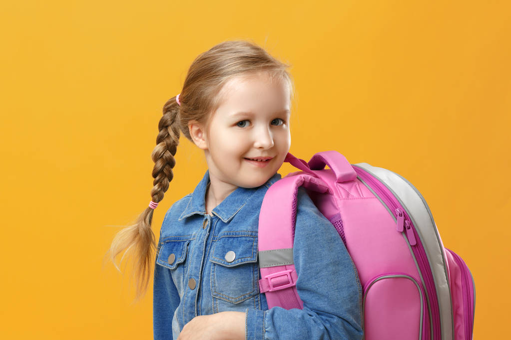 Portrait of a little girl schoolgirl with a backpack on a yellow background. Back to school. The concept of education. - Photo, Image