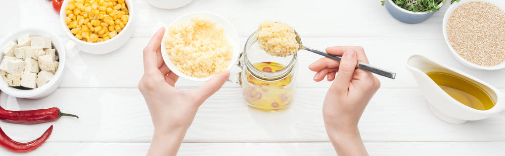 cropped view of woman adding couscous to glass jar on wooden white table, panoramic shot - Photo, Image
