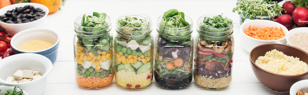 köstlicher Gemüsesalat in Glasgläsern auf weißem Holztisch isoliert auf weißem, panoramischem Foto - Foto, Bild