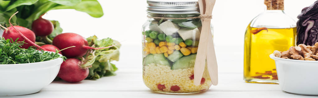 colpo panoramico di insalata di verdure fresche in vaso di vetro vicino a olio e ravanello isolato su bianco
 - Foto, immagini