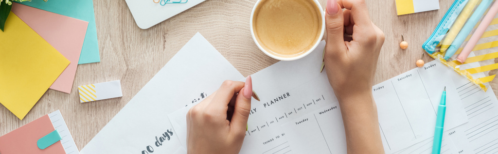 cropped view of woman with cup of coffee holding hands on planners and check lists - Photo, Image