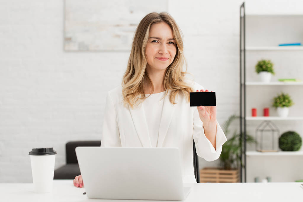 pretty businesswoman looking at camera and showing blank empty business card - Photo, Image