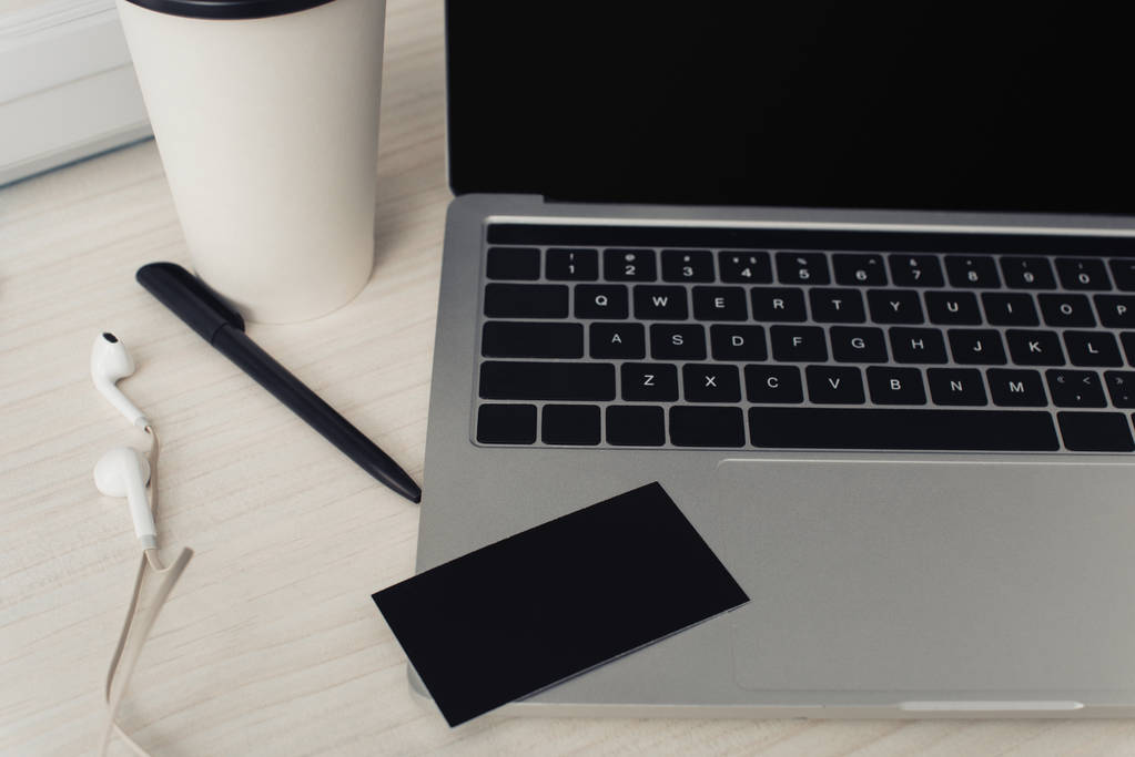 Czarna pusta wizytówka na klawiaturze laptopa, długopis i słuchawki na stole biurowym - Zdjęcie, obraz