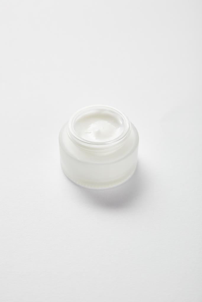 frasco de vidrio abierto con crema facial en blanco
  - Foto, Imagen
