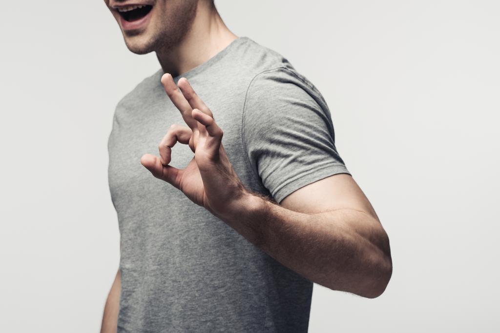 wykadrowany widok młodego mężczyzny przedstawiający gest OK wyizolowany na szaro, ludzką emocję i koncepcję ekspresji - Zdjęcie, obraz