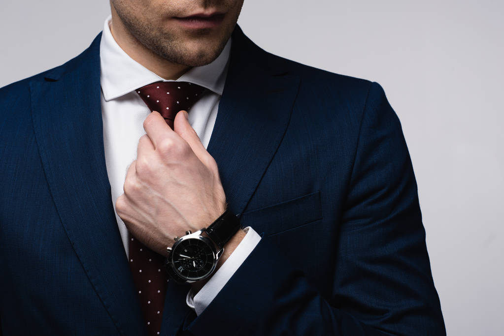частичный взгляд бизнесмена трогательный галстук изолирован на серый
 - Фото, изображение