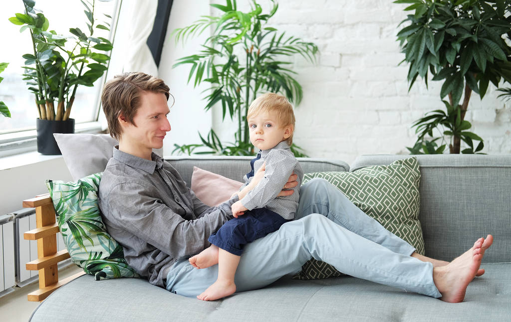 ライフスタイル、家族、人々のコンセプト - 自宅で遊ぶ彼の1歳の息子と幸せな若い父親 - 写真・画像
