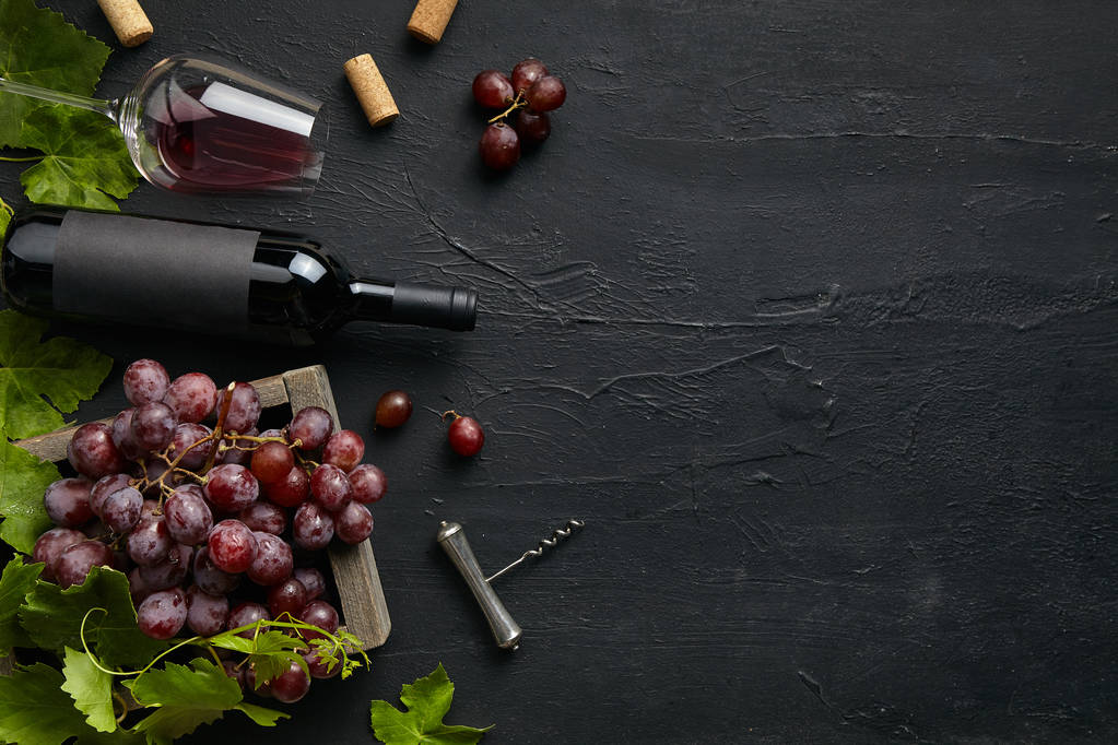 Vista dall'alto del gustoso piatto di frutta con la bottiglia di vino sulla pietra nera
 - Foto, immagini
