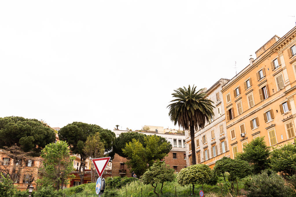 úttábla, zöld fák és bokrok közelében színes épületek Rómában, Olaszországban - Fotó, kép