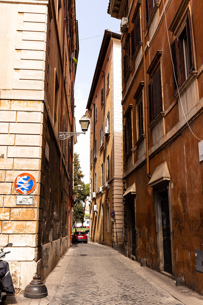 Rome, Italië-28 juni 2019: smalle straat en rode auto in zonnige dag in Rome, Italië - Foto, afbeelding