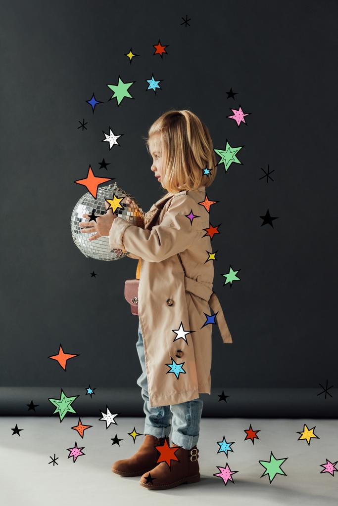 vista lateral del niño en gabardina sosteniendo bola disco sobre fondo negro con ilustración de estrellas
 - Foto, imagen