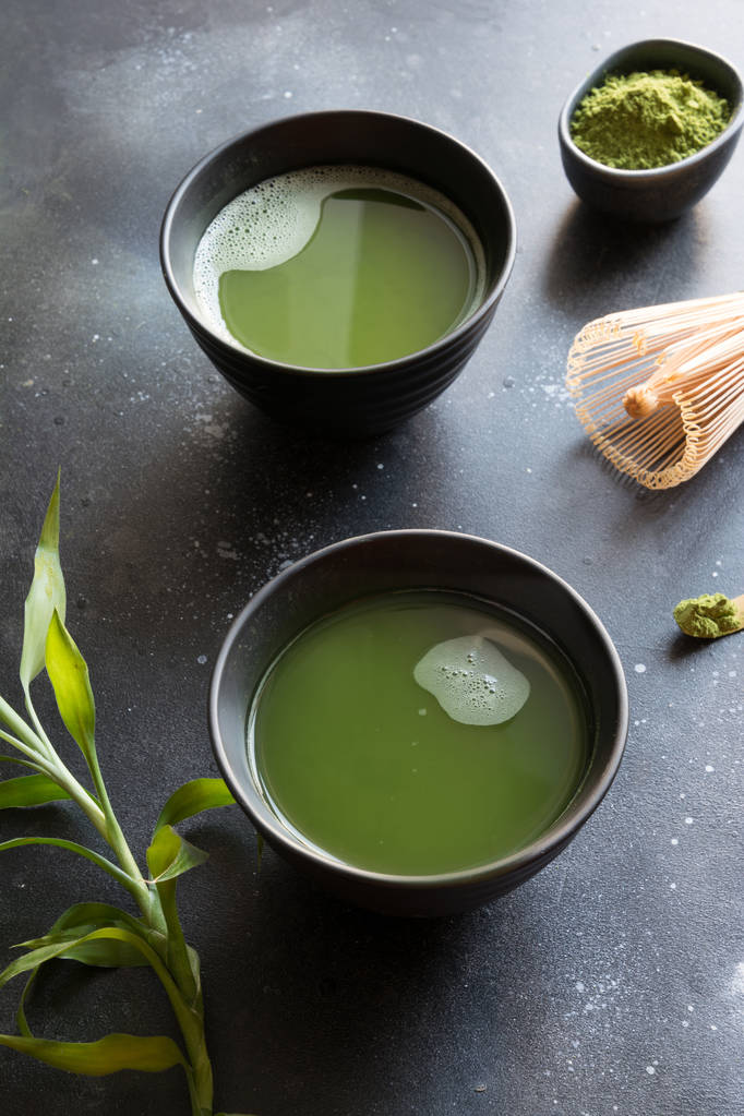 Orgánica de dos té matcha verde en tazón sobre mesa negra
. - Foto, Imagen