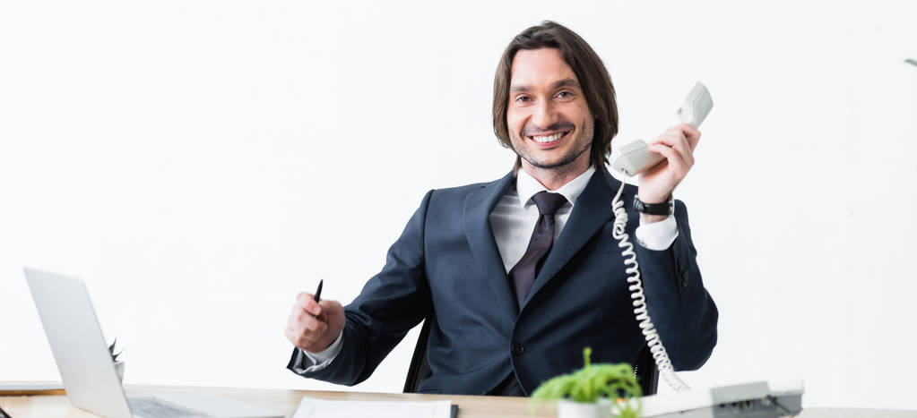 Panoramaaufnahme eines glücklichen Geschäftsmannes mit Headset in der Hand und Blick in die Kamera - Foto, Bild