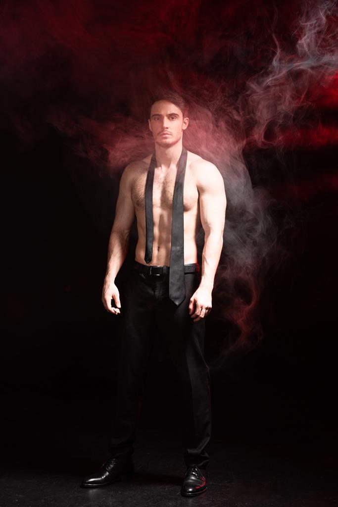 vue pleine longueur de sexy homme torse nu debout en fumée sur noir
 - Photo, image
