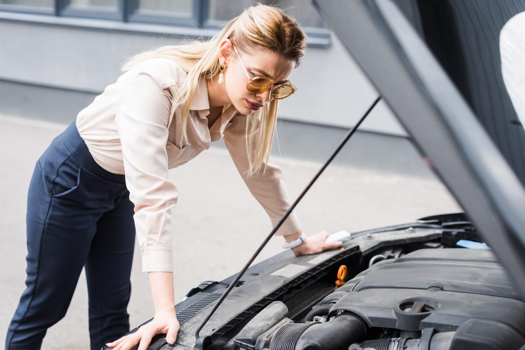 businesswoman standing near broken auto and looking at open trunk, car insurance concept - Photo, Image