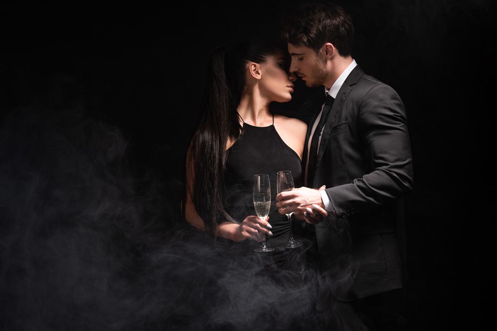 Stylový pár s brýlemi na šampaňském, líbání na černém - Fotografie, Obrázek