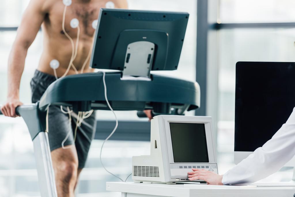 Ausgeschnittener Blick auf Arzt bei Härtetest mit Sportler im Fitnessstudio - Foto, Bild