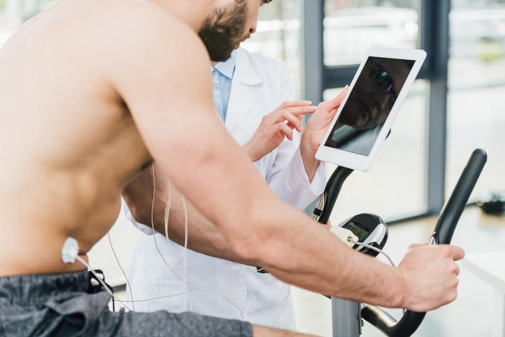 Vágott orvoshoz, digitális tabletta közelében félmeztelen sportoló alatt tartóssági vizsgálat - Fotó, kép