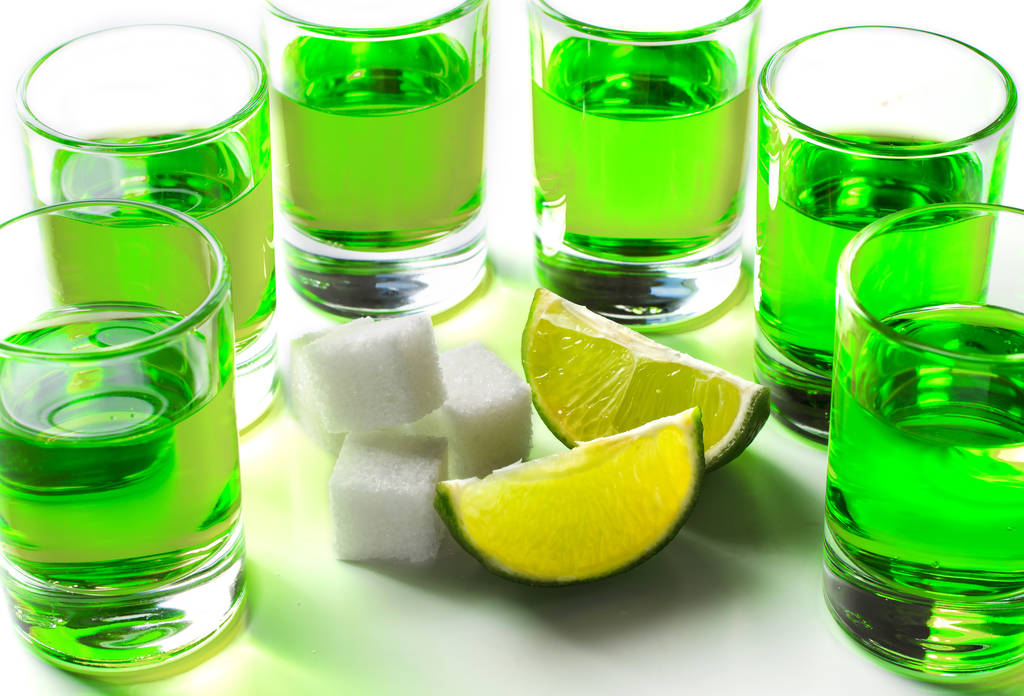 Licor verde ajenjo en vasos. Bebida alcohólica alucinógena. Fondo blanco. Trozos de cal y azúcar blanca
. - Foto, imagen