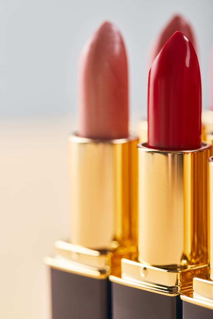 Close-up van verschillende rode lippenstift in tubes op beige  - Foto, afbeelding