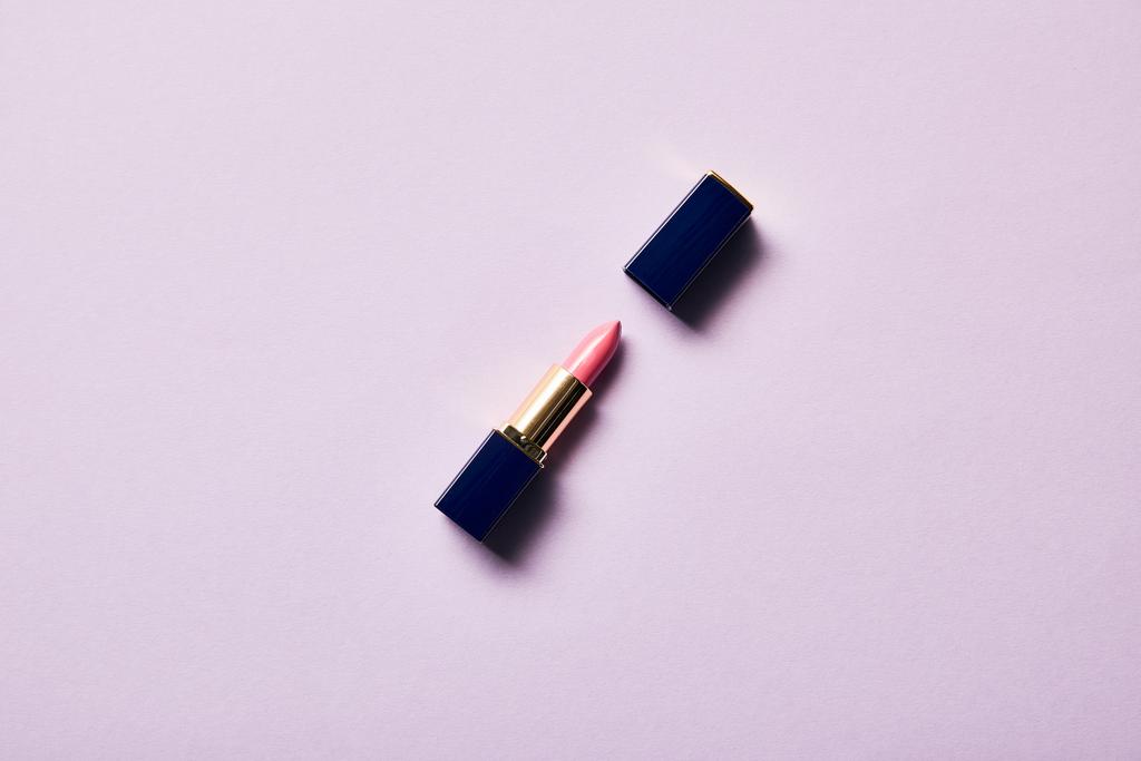 vista dall'alto di singolo tubo aperto di rossetto rosa su viola
 - Foto, immagini