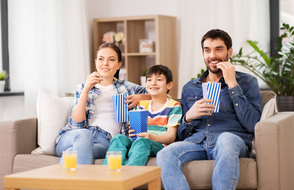 familia feliz con palomitas de maíz viendo la televisión en casa
 - Foto, Imagen