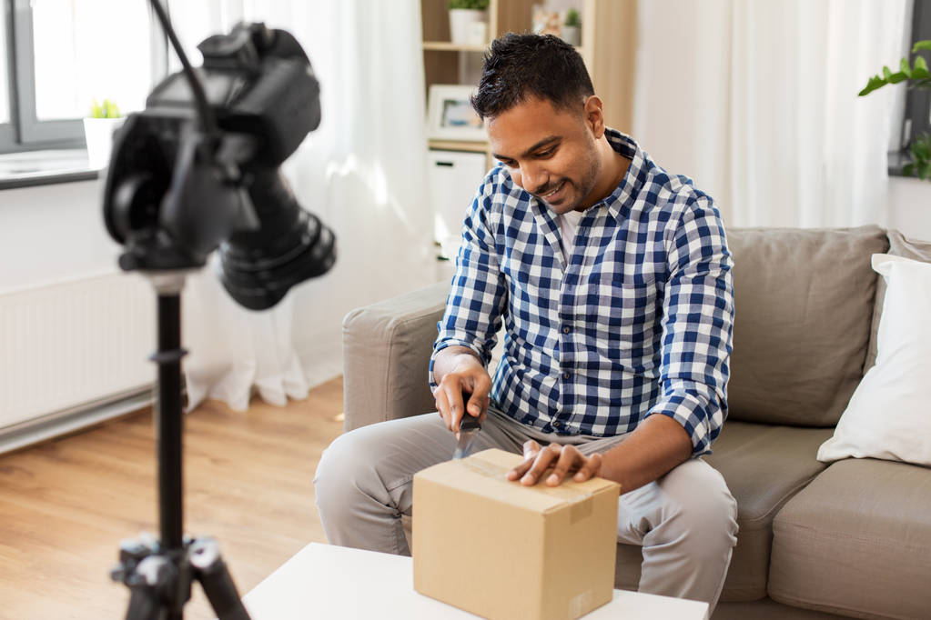 mannelijke video blogger openen pakket doos thuis - Foto, afbeelding