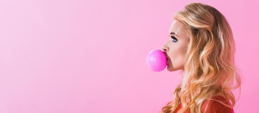 panoramatický záběr krásné dívky foukající žvýkačky izolovaná na růžových, panenský koncept - Fotografie, Obrázek