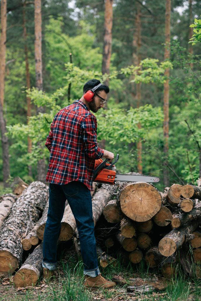 bois barbu dans les protecteurs auditifs tronc de coupe avec tronçonneuse dans la forêt
 - Photo, image
